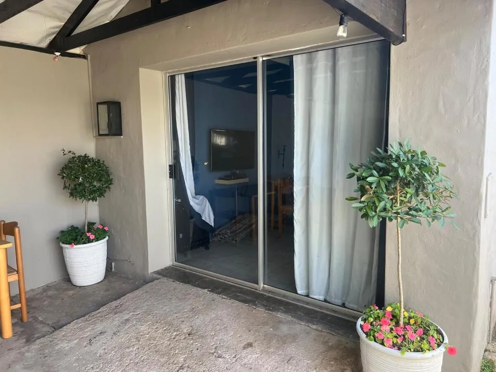 Cabana entrance terrace at dusk with potted olive trees, fairy lights and glass sliding doors
