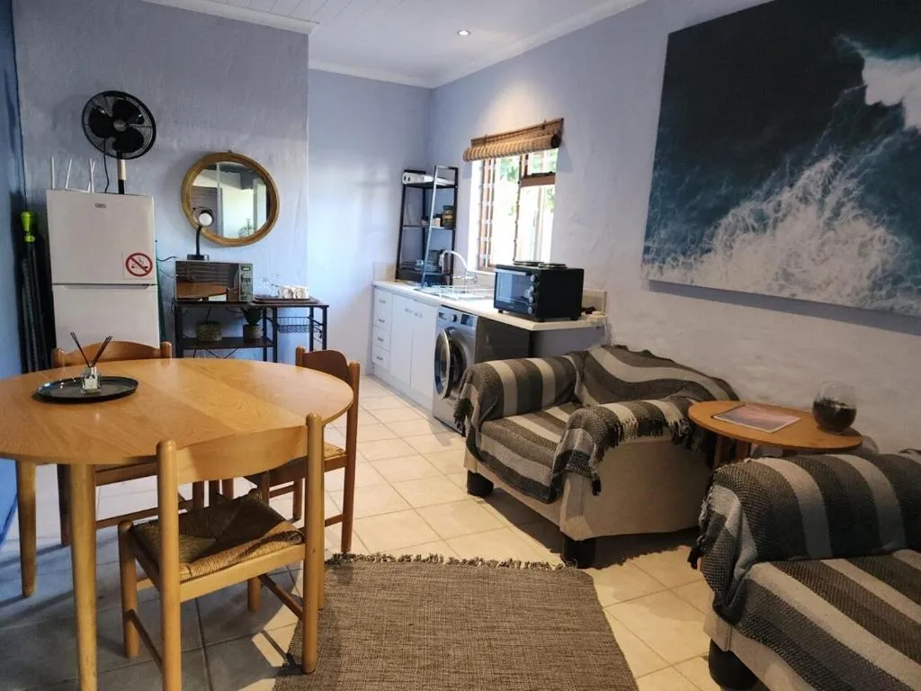 Open-plan lounge and kitchenette with a striped sofa, round dining table and a wave-artwork canvas