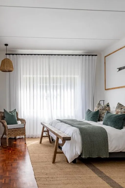 Second bedroom with sheer curtains, a wicker chair and green woven cushions