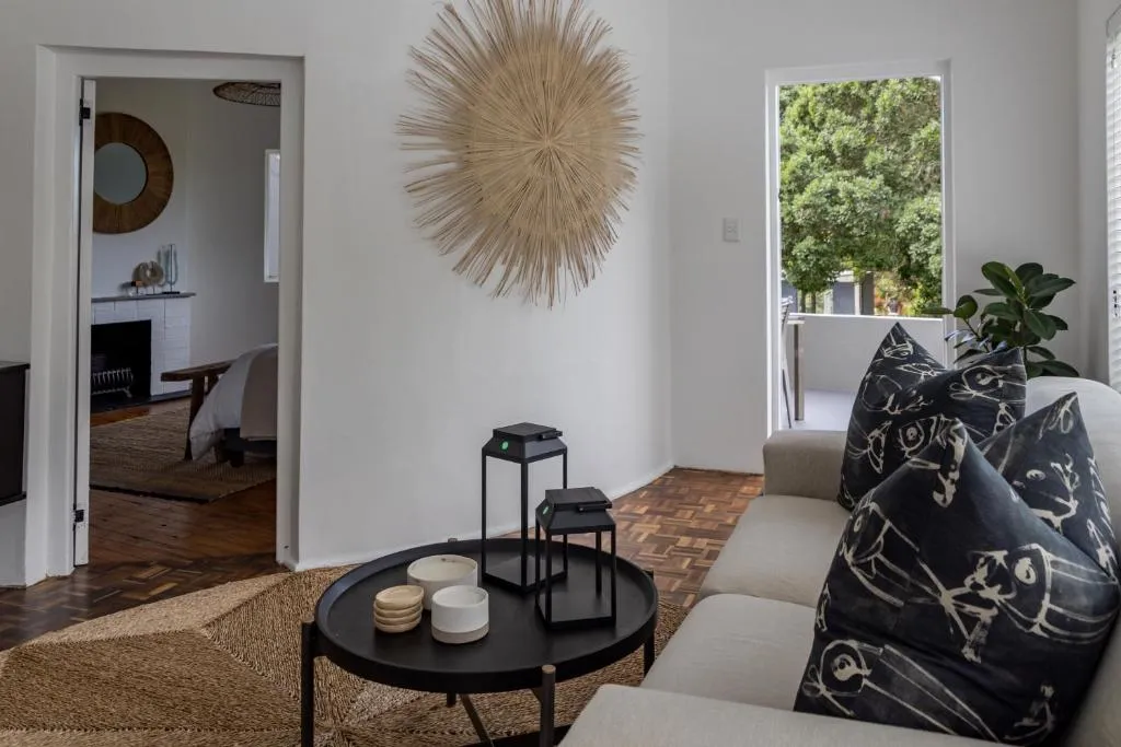 Living room with sunburst wall art and a glass door onto a leafy balcony