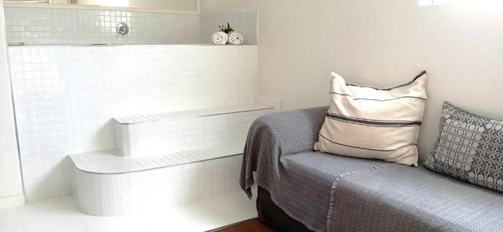 Tiled step-up bath area beside a cushioned lounge nook with folded towels