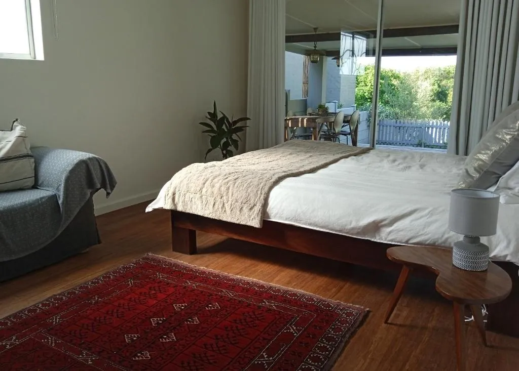 Bedroom with a low platform bed and sliding glass doors opening onto the deck and garden