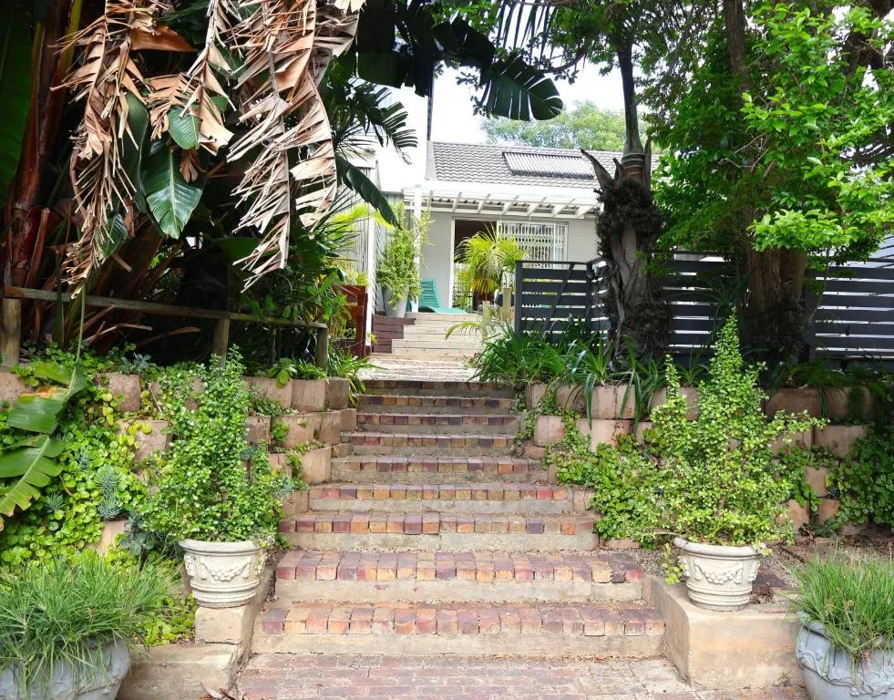Brick garden steps rising through lush tropical foliage to the house entrance