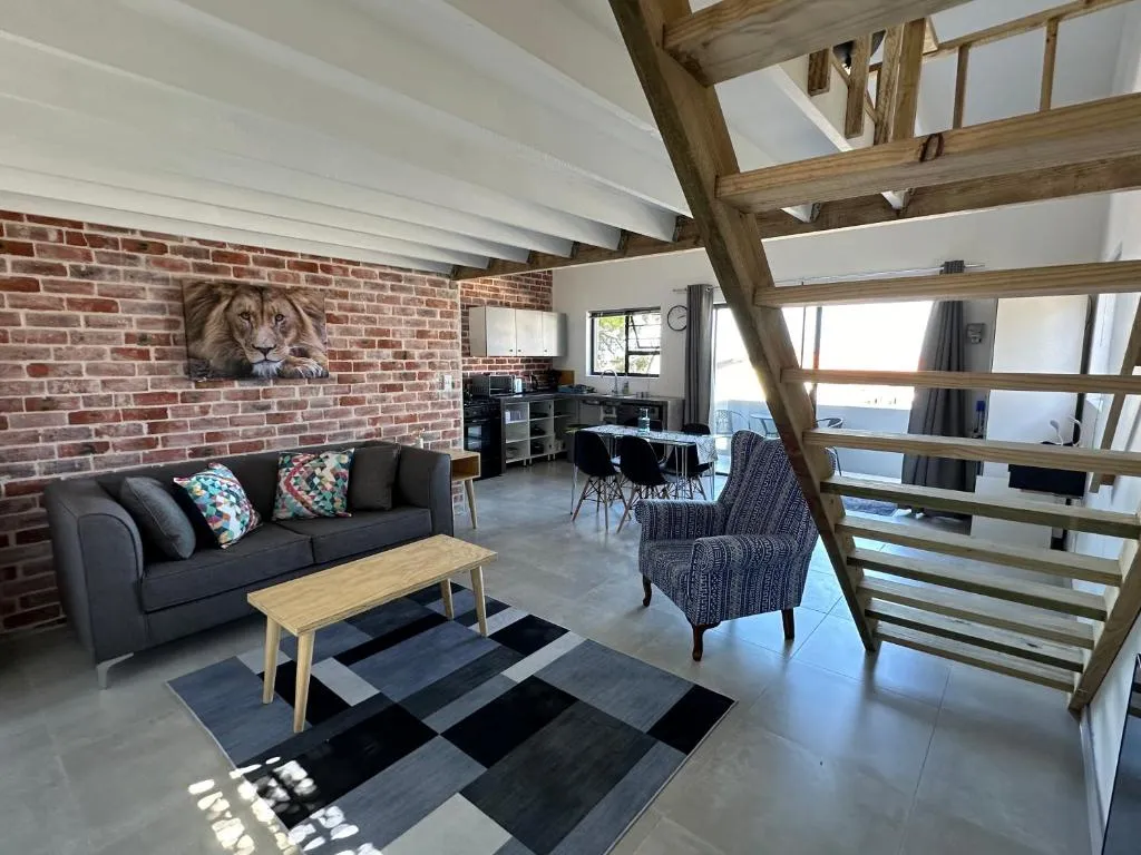 Living area with a grey sofa, lion canvas print on exposed brick and an open kitchen beyond