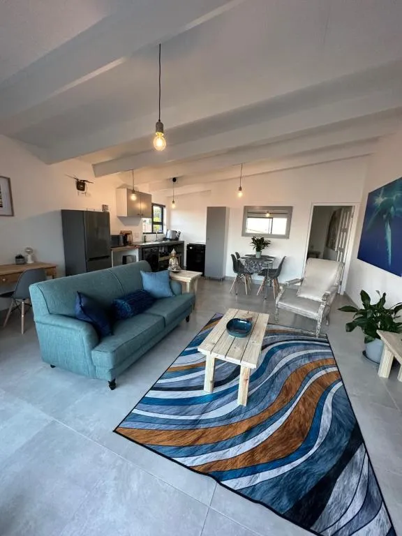 Living room with a teal sofa, hanging pendant light and an open-plan kitchen