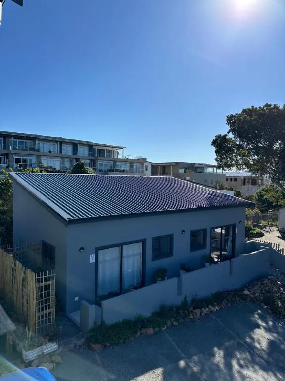 Exterior of a single-storey unit with a dark standing-seam roof and a small paved courtyard