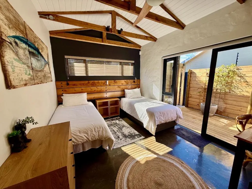 Twin beds beneath a raftered ceiling, facing a fish-artwork triptych