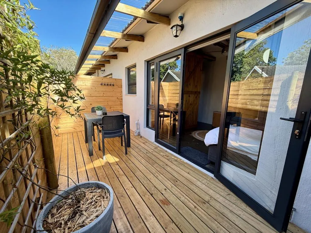Wooden deck with outdoor dining table, leading to the bedroom's glass doors