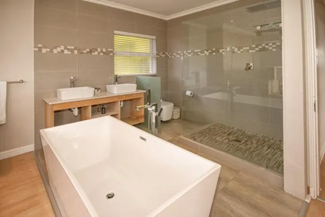 Bathroom with a freestanding tub, double vanity and a separate glass-walled shower