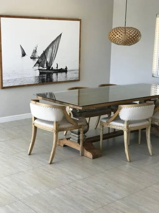 Dining area with a glass-topped table on rustic timber legs and a black-and-white sailing print