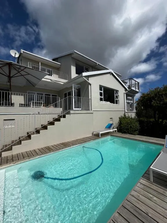 Double-storey house with a wooden sundeck and pool beneath a dramatic cloudy sky