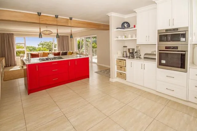 Kitchen with a bold red island unit, gas hob and built-in double oven