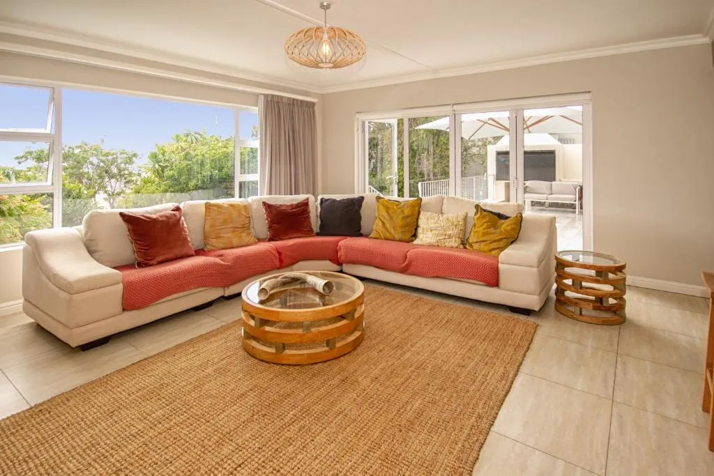 Corner sofa in cream and coral facing tall windows onto trees and a covered outdoor lounge