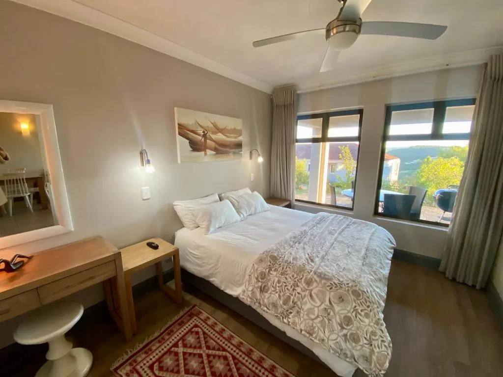 Second bedroom with a boat painting, ceiling fan, and windows looking over the estate's hills