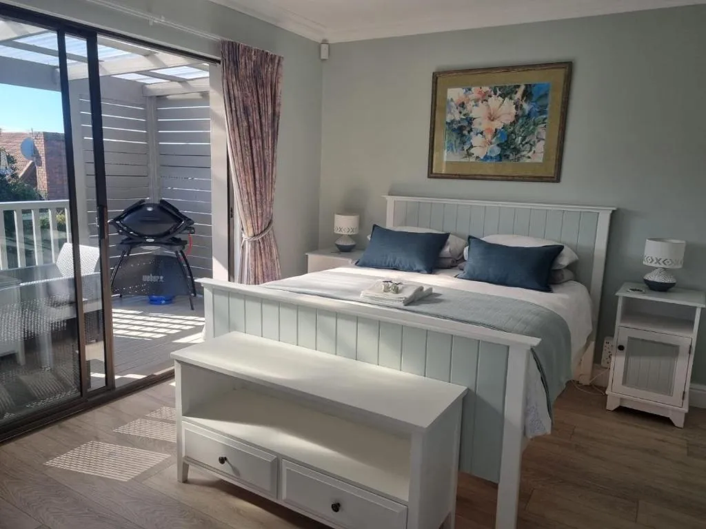 Bedroom with sliding doors onto a balcony fitted with a Weber kettle braai