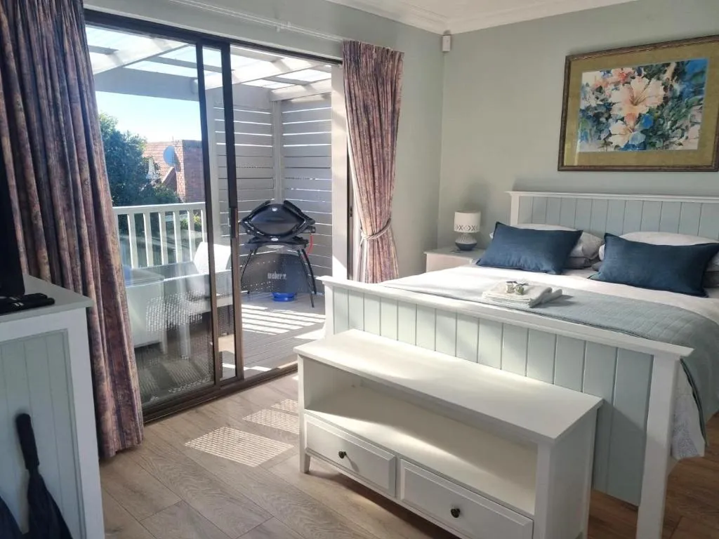 Bedroom opening onto a slatted-screen balcony with a portable braai