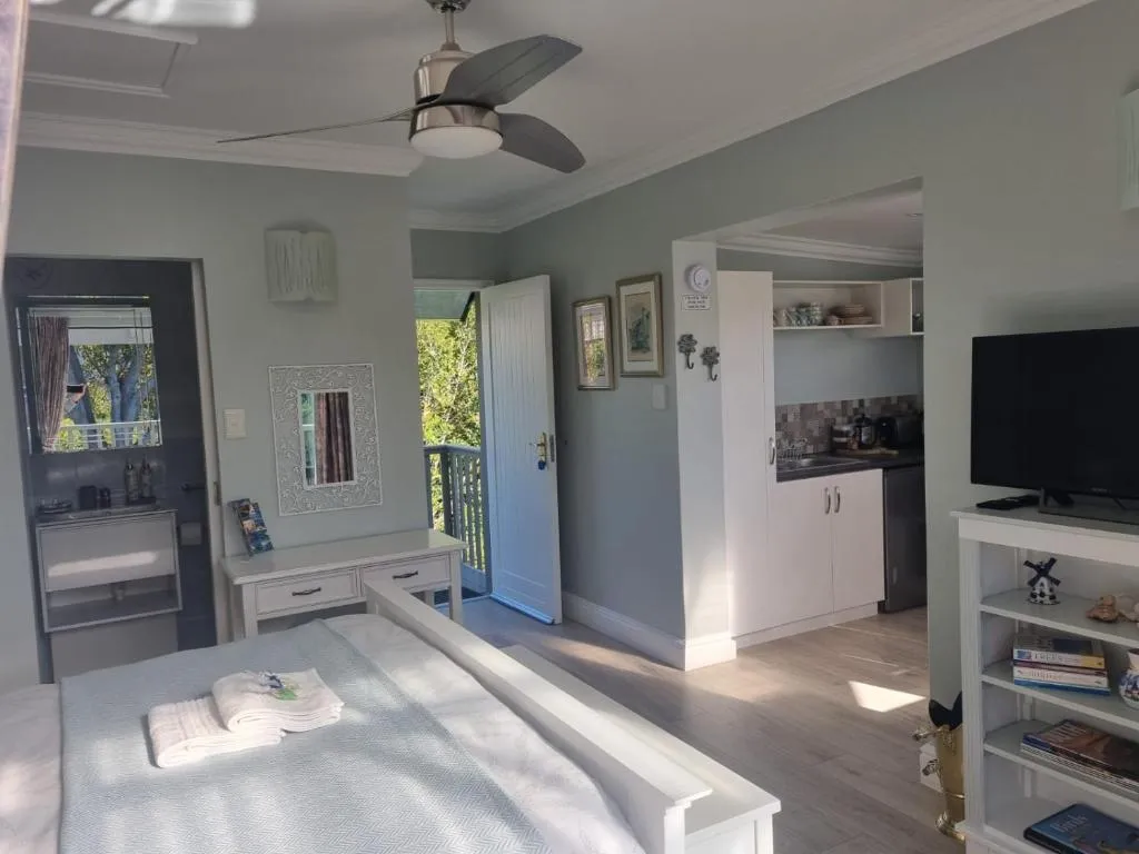 Corner kitchenette with white cabinetry, ceiling fan and open balcony door