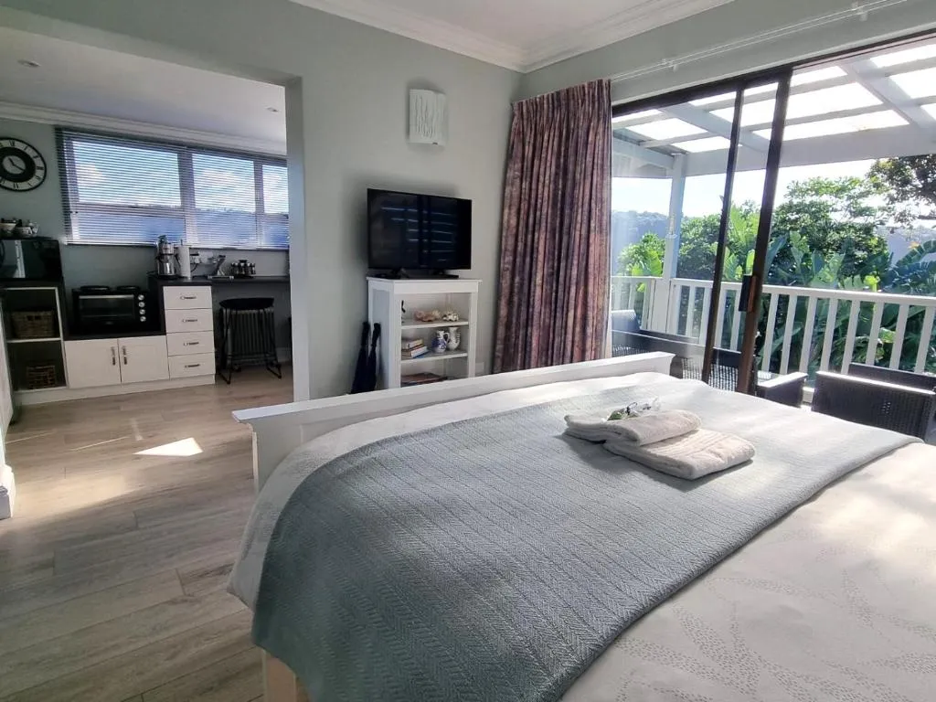 Studio combining bed, kitchenette and a pergola-covered balcony in one open space