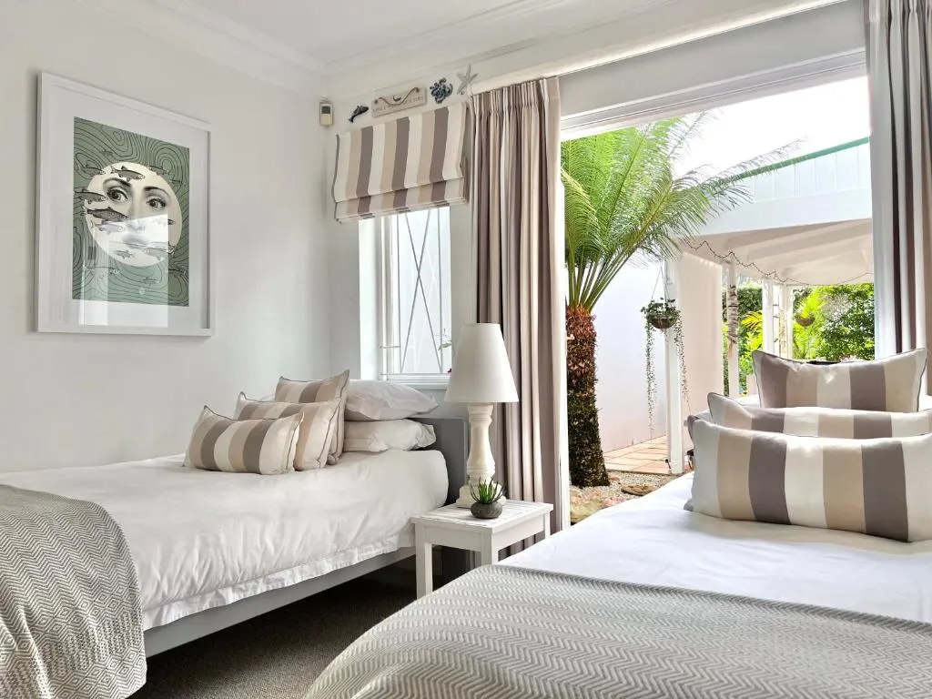 Bedroom with striped cushions and a sliding door onto a covered, palm-shaded porch