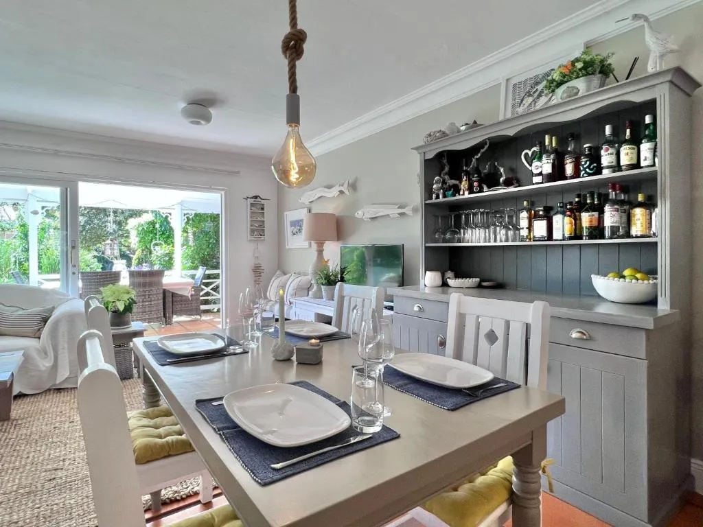 Dining table set for four beside a stocked drinks dresser, with garden views through the doors