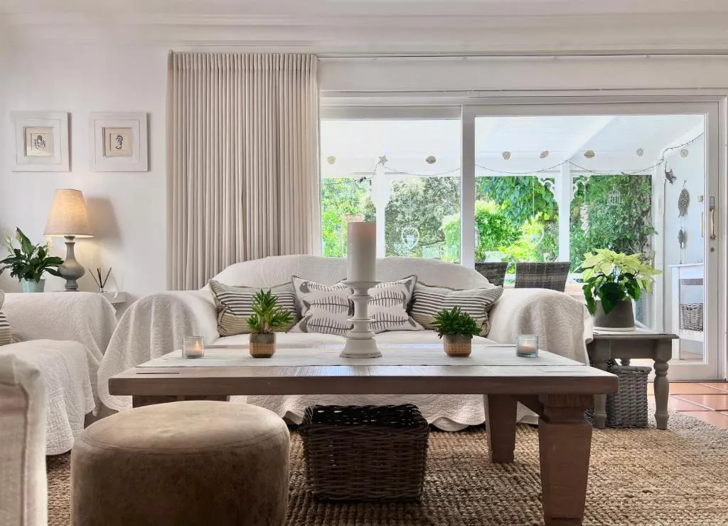 Living room with slipcovered sofas opening via sliding doors onto a plant-filled veranda