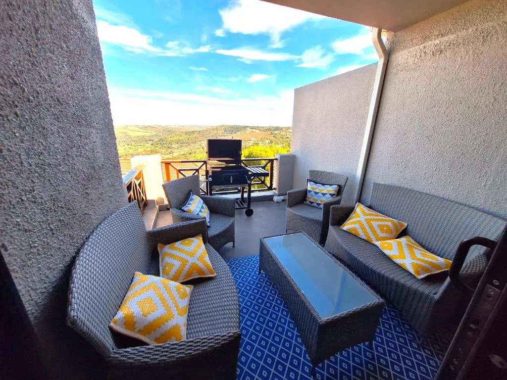Balcony with wicker seating, a braai and a view over the green valley