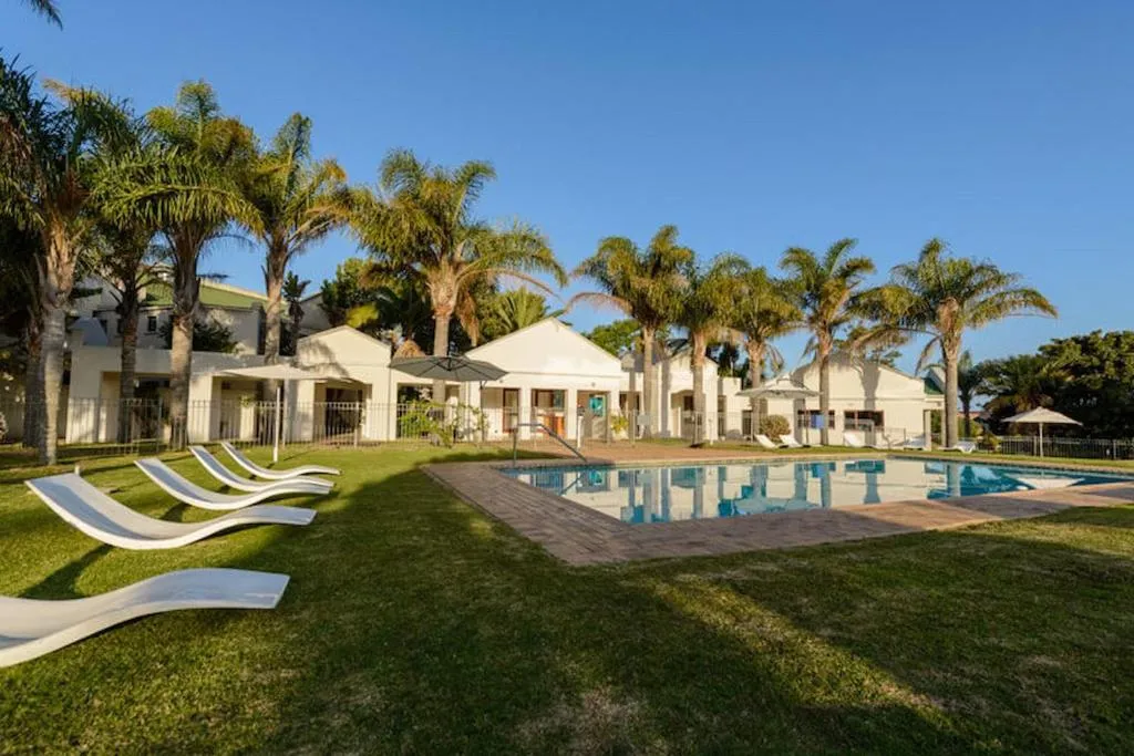 Communal pool area with loungers, palm trees and the estate's clubhouse