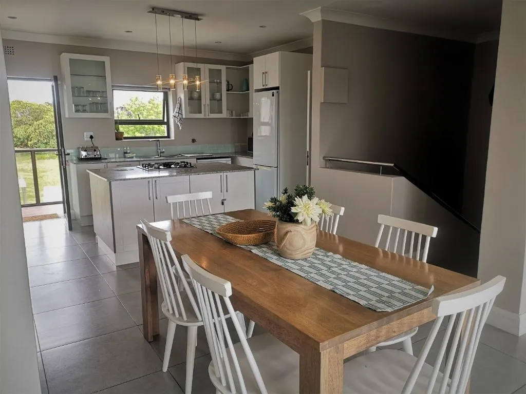 Open-plan kitchen with white cabinetry and a wooden dining table set for six
