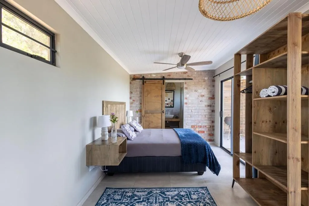 Bedroom with exposed brick wall and a sliding barn door to the en-suite bathroom
