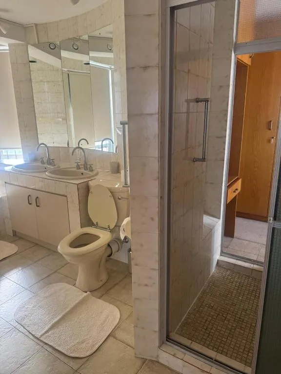 Bathroom with a double vanity, mirrored wall and a separate glass-enclosed shower stall