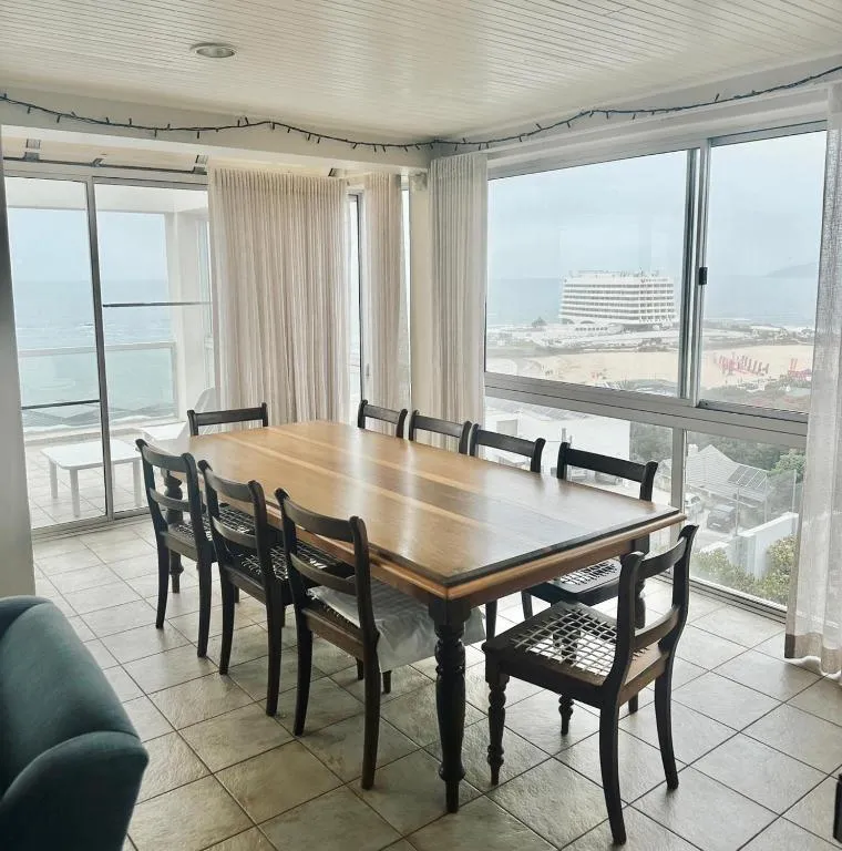 Dining table for eight beside floor-to-ceiling windows overlooking the beach and Beacon Island