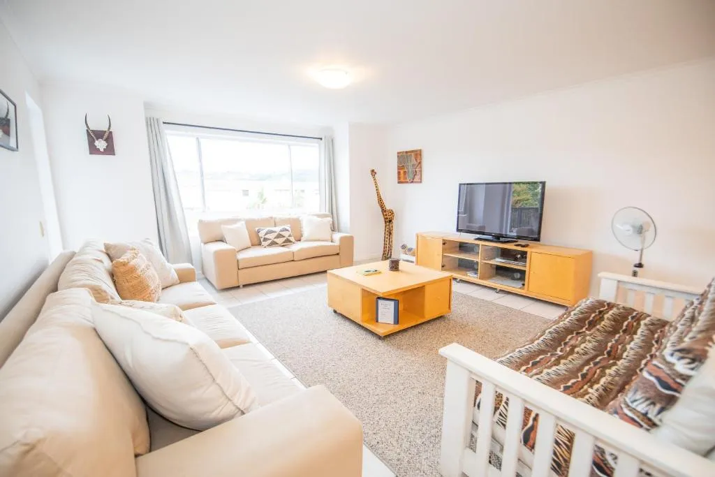 Living room with a cream L-shaped sofa, wooden TV unit and window view