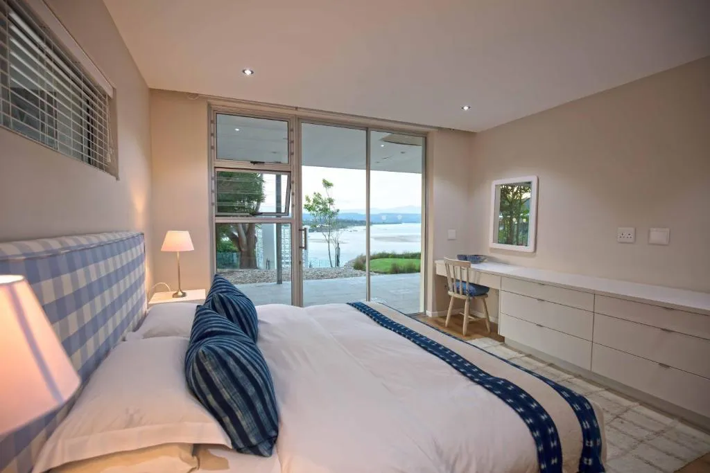 Bedroom with a checked headboard and sliding doors opening onto the lagoon and sea view