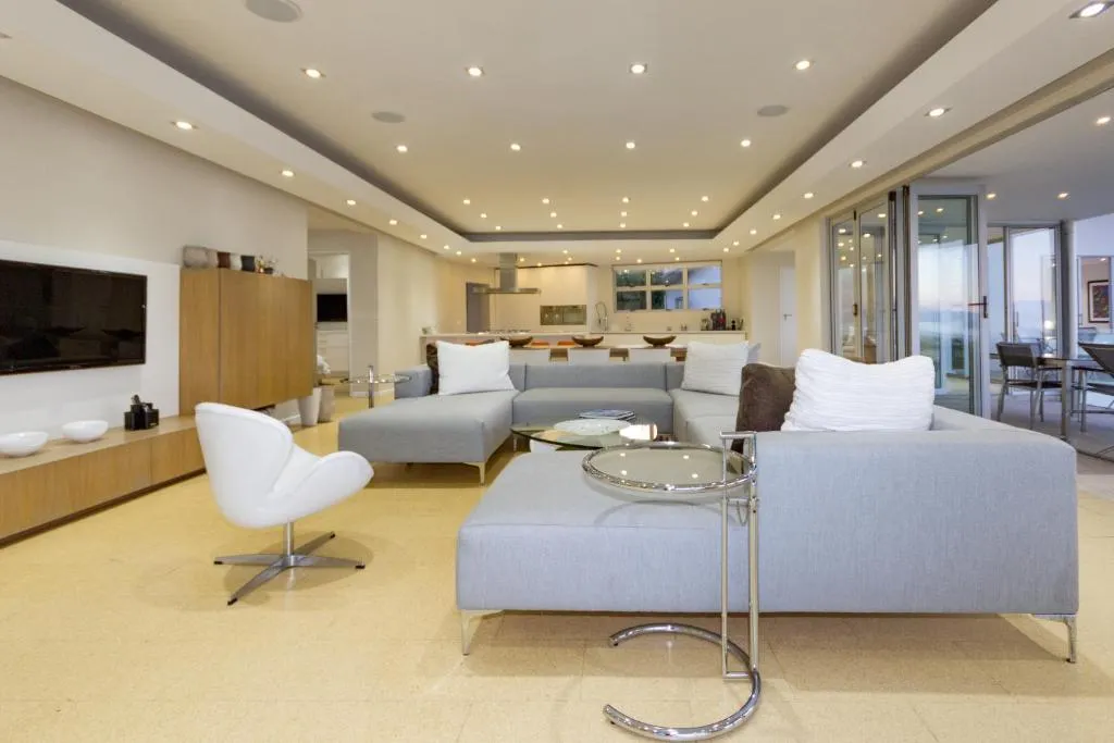 Open-plan living room with grey sofas, a TV wall and the kitchen visible in the background