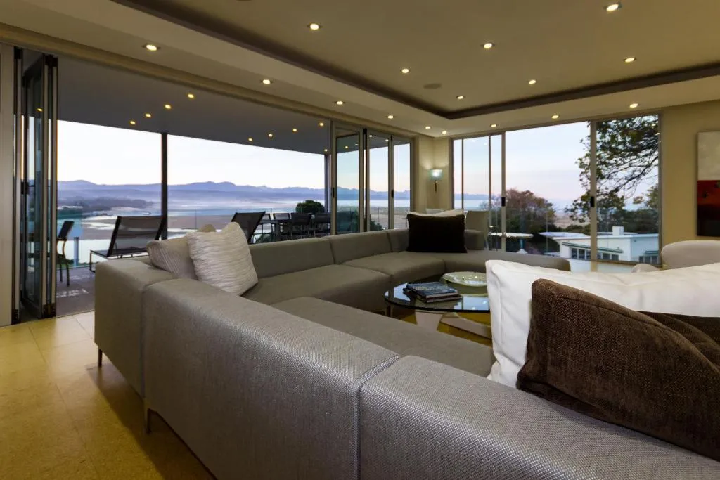 Sectional lounge suite facing floor-to-ceiling windows over the lagoon and coastline
