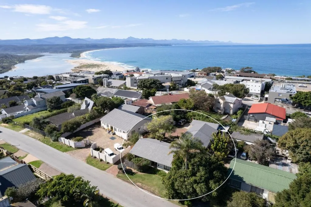 Aerial view of the property circled within its street, with the beach beyond