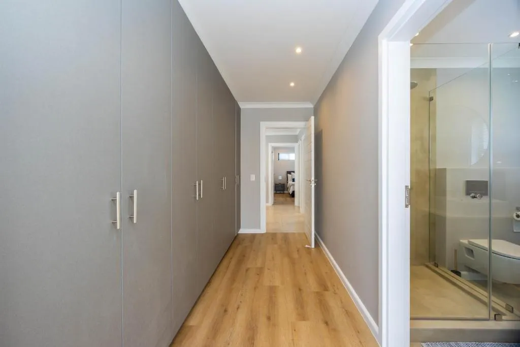 Wardrobe-lined hallway leading to an en-suite bathroom with a glass-walled shower