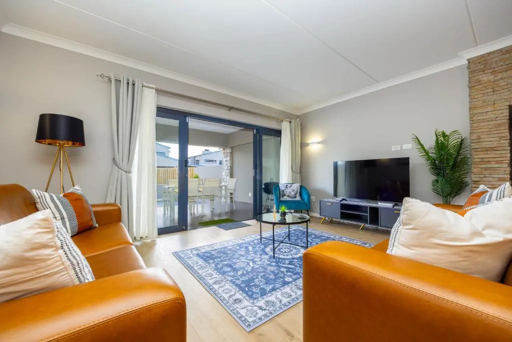 Living room with leather armchairs opening via sliding doors onto an outdoor patio with dining setting