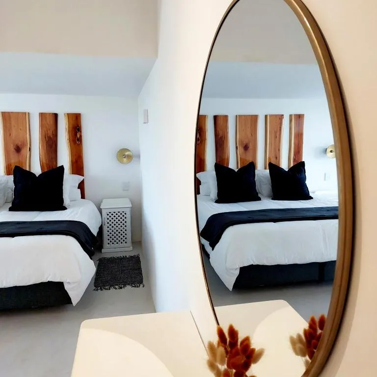 Bedroom reflected in a round mirror, showing a bed with a live-edge wood headboard and navy pillows