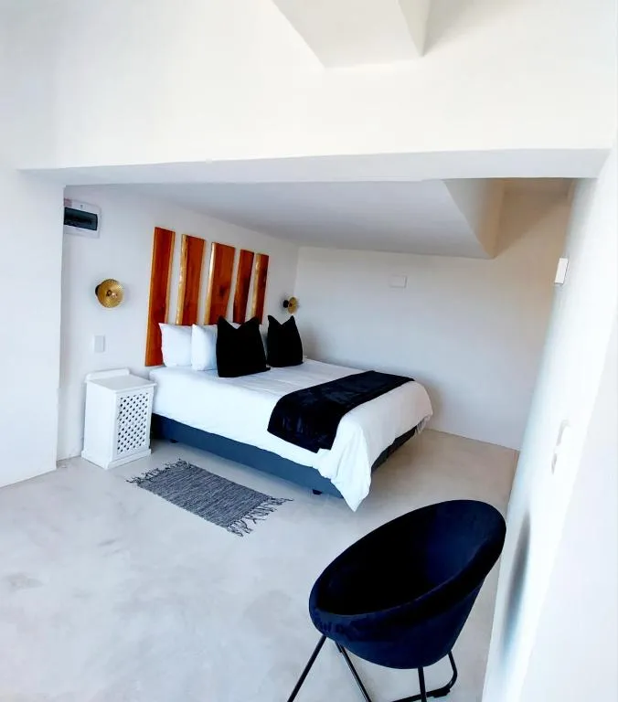 Bedroom with a vaulted ceiling, live-edge timber headboard, and a black velvet accent chair