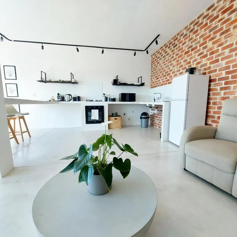 Open-plan living area with an exposed brick wall, kitchenette, and a round coffee table