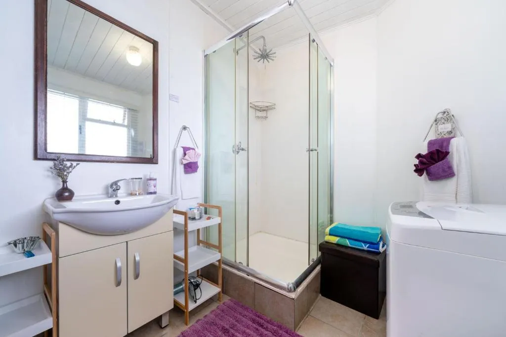 Second bathroom with a corner shower, vanity, and a washing machine beside the shower