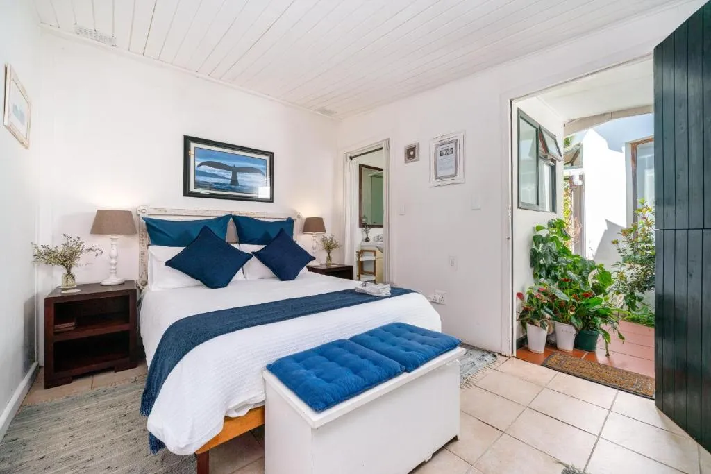 Bedroom with a whale-tail photograph, navy cushions, and doors opening onto a plant-filled courtyard
