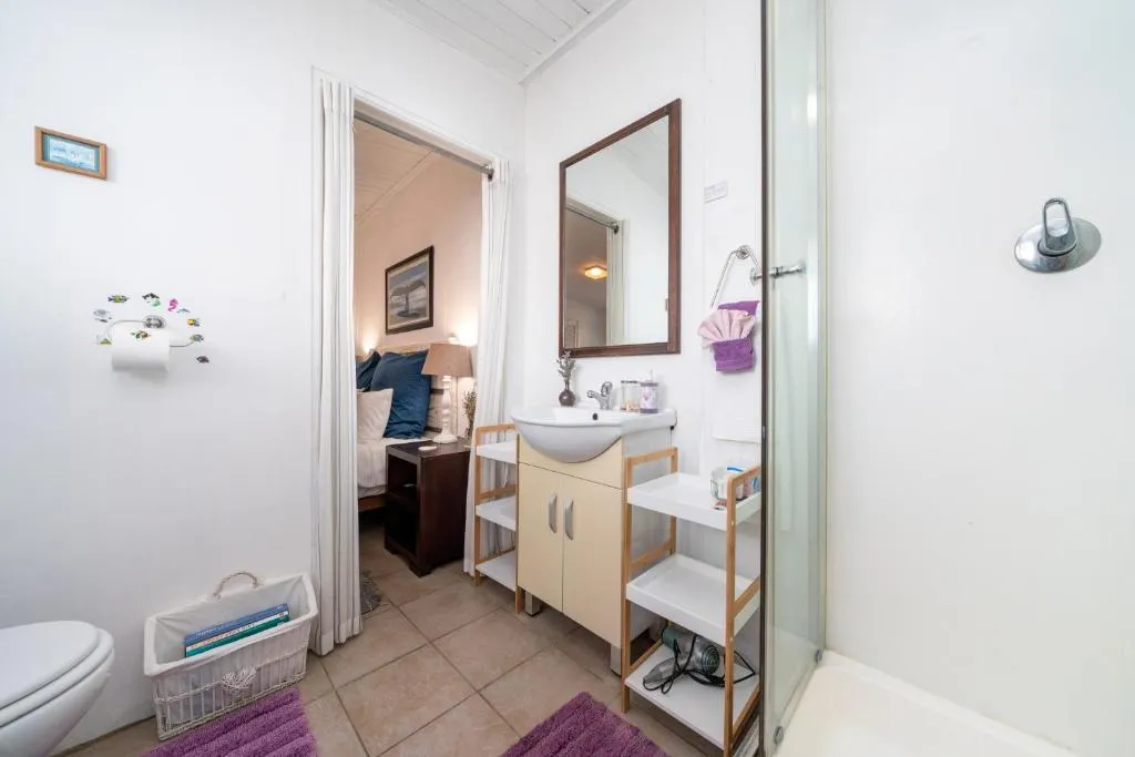Ensuite bathroom with a wood-framed mirror, pedestal-style vanity, and a view through to the bedroom