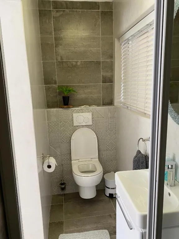 Guest toilet and washbasin finished in charcoal tile with a woven bath mat