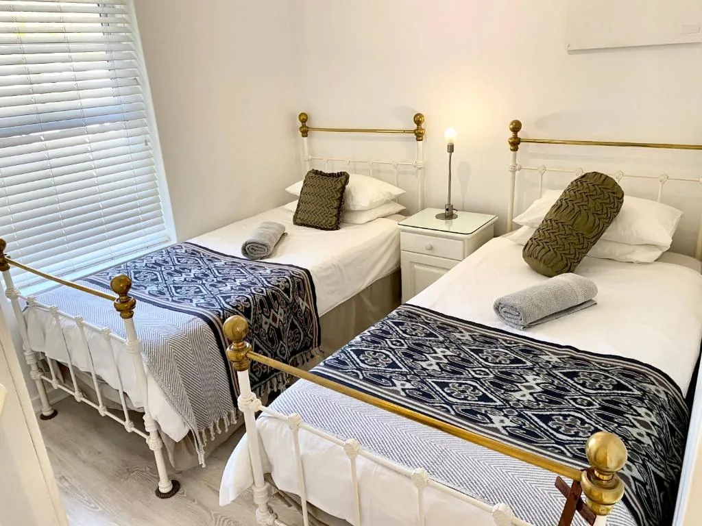 Twin bedroom with brass-topped iron bed frames and patterned ikat throws