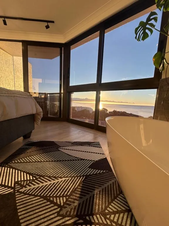 Bathroom with a freestanding tub positioned beside floor-to-ceiling windows over the ocean