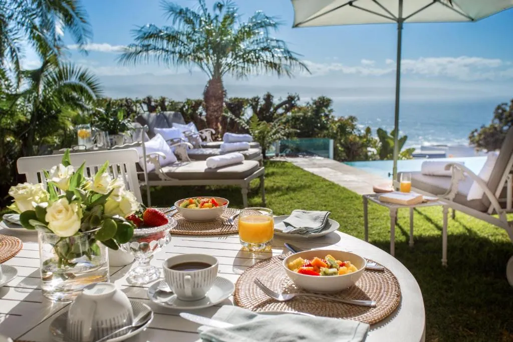 Outdoor breakfast table set beside the pool with a sea view beyond