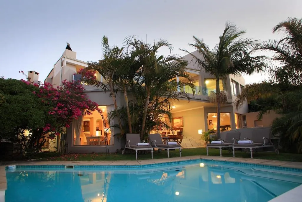 Twilight view of the house and pool framed by palm trees and bougainvillea