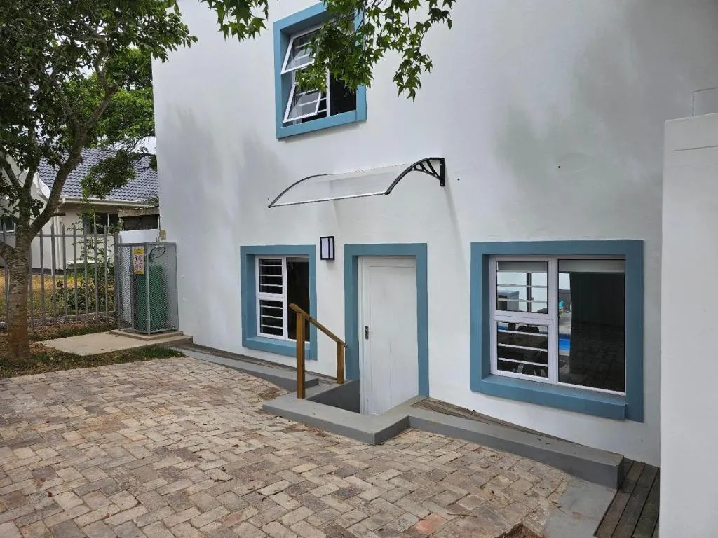 Building entrance with blue-trimmed windows, a canopy over the door and a paved courtyard